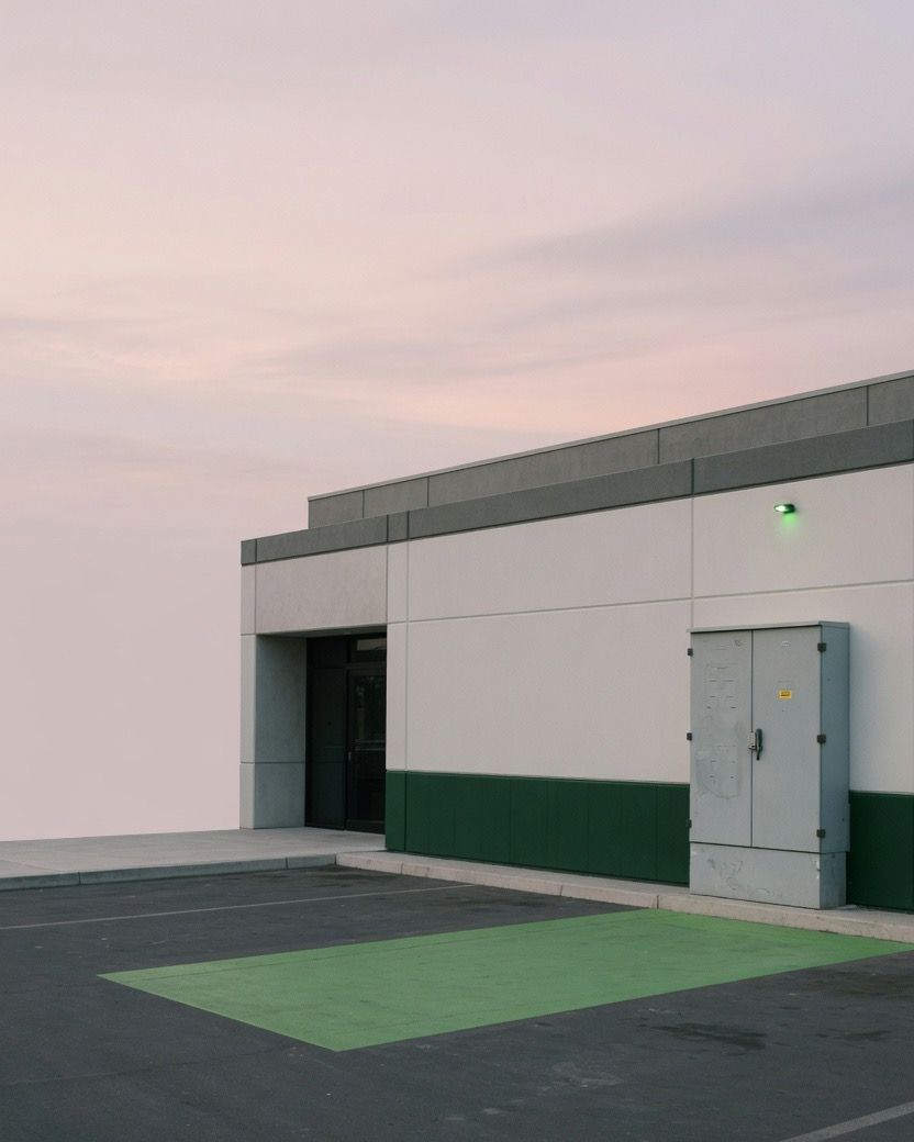 Facade of a commercial building at dusk, with a spot painted green in the parking lot out front.