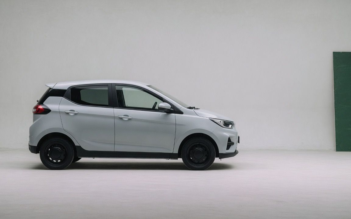 Carro elétrico compacto de perfil num estúdio cinza-claro, sem emblemas.