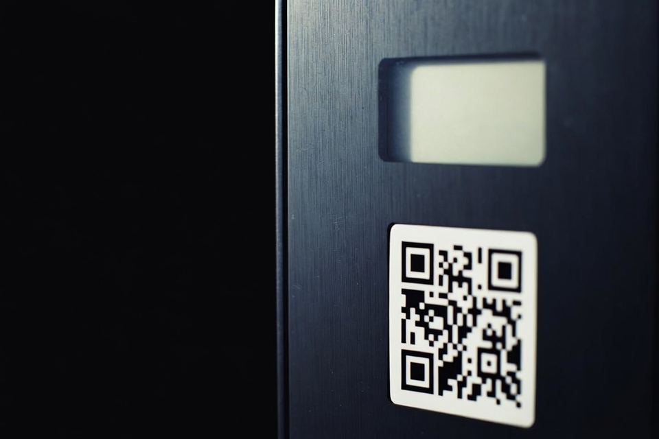 Painel de um carregador, com o visor acima e o adesivo de QR code colado abaixo dele.