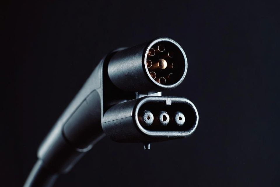 Conector de recarga rápida visto de frente, com a seção redonda de pinos em cima e a seção oval embaixo.